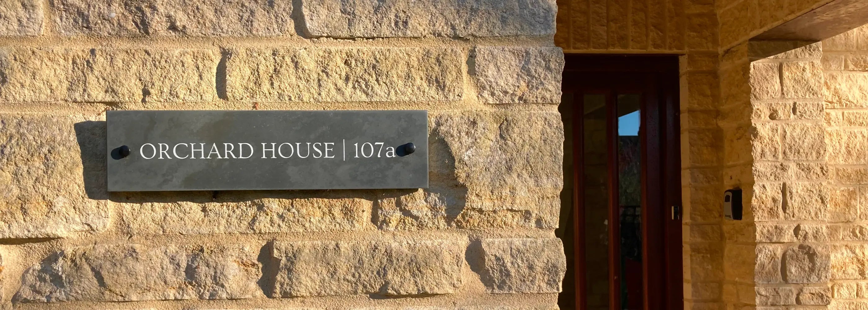 Stonework exterior with 'Orchard House 107' sign