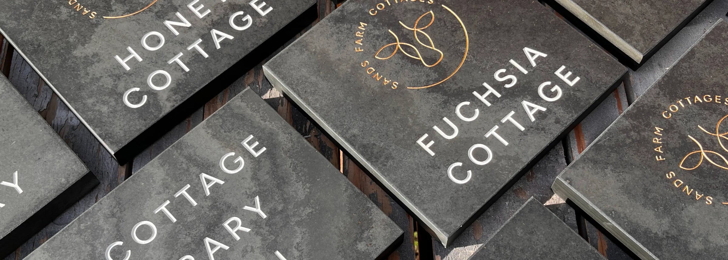 Set of slate signs with 'Home Cottage' and 'Fuchsia Cottage' text on a dark background
