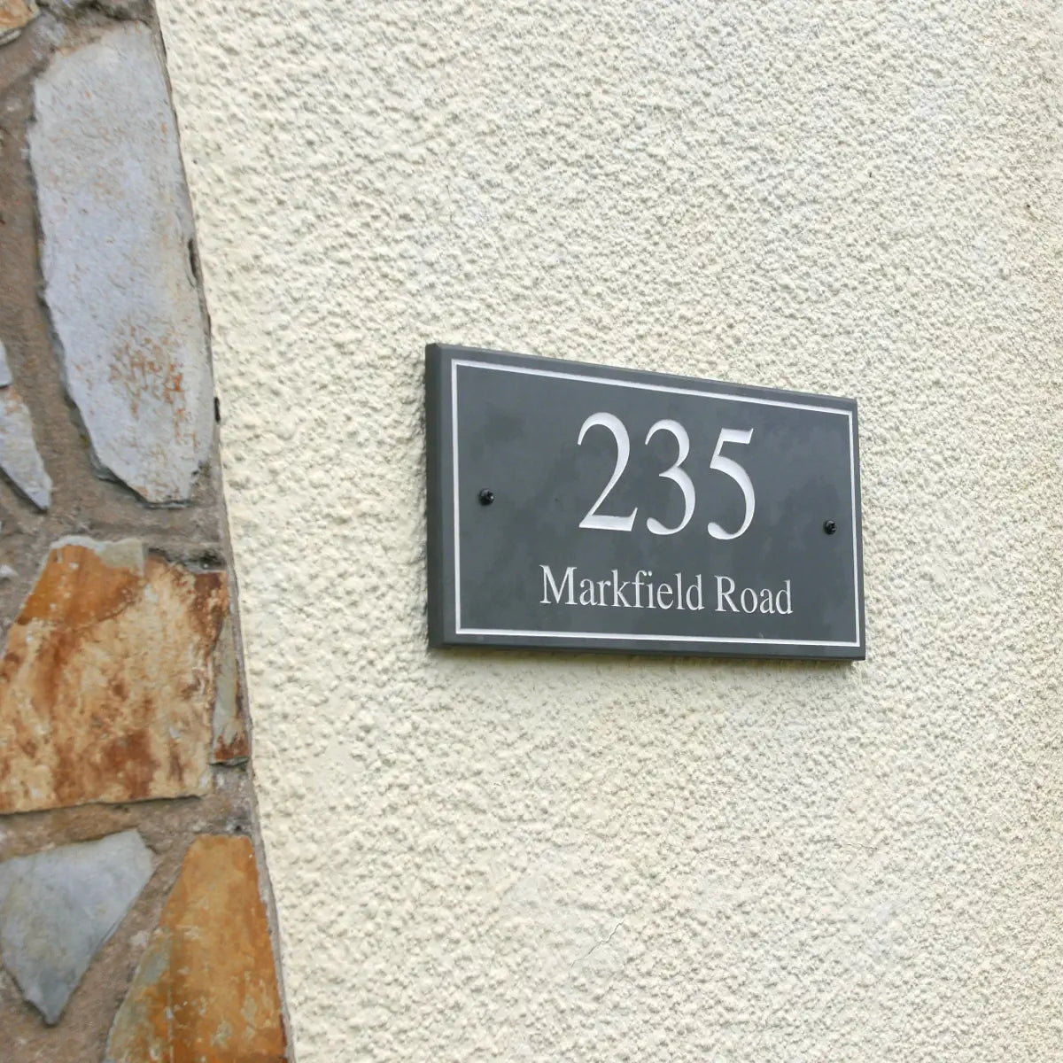 House number sign '235 Markfield Road' on a textured wall.