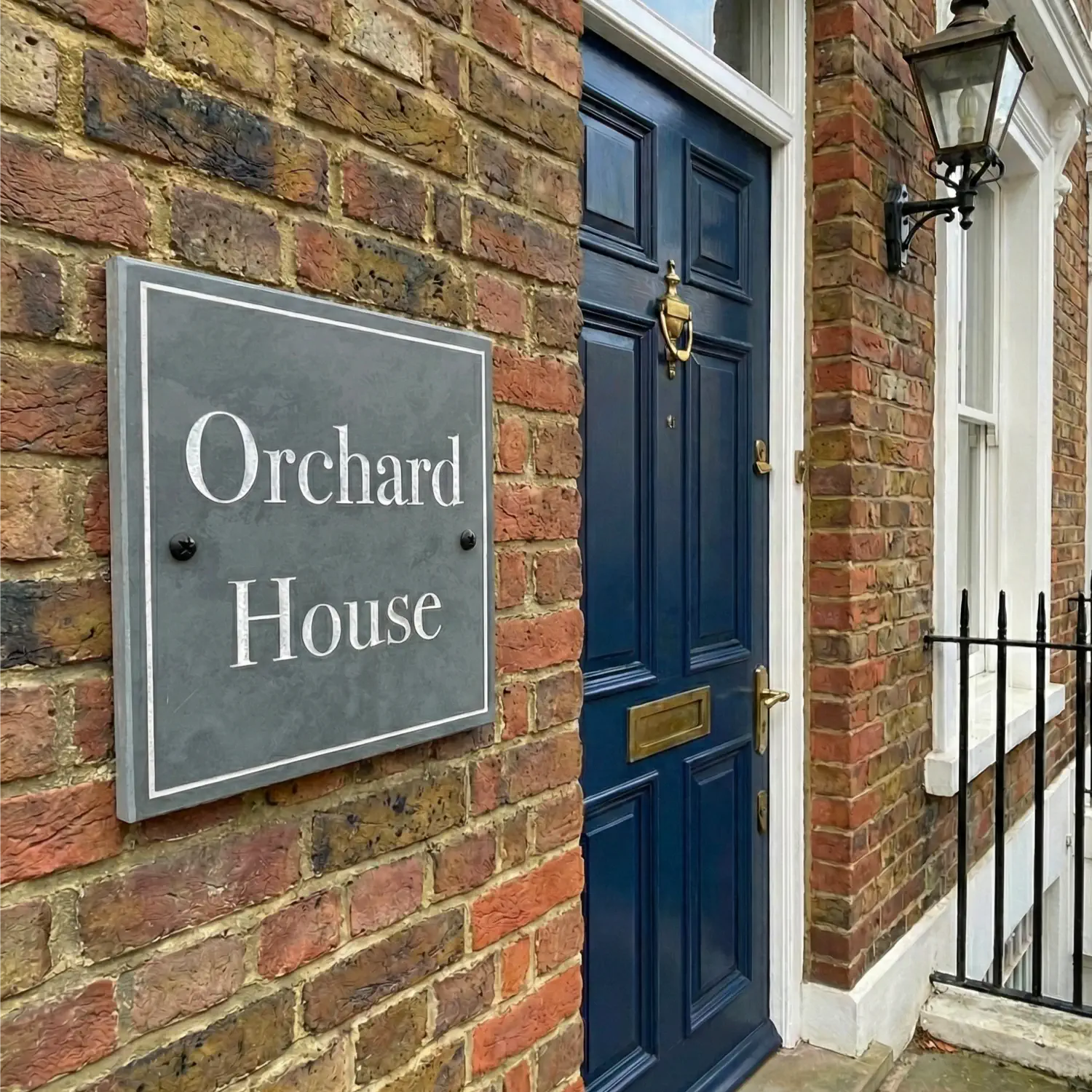 Blue door of Orchard House with a sign on a brick wall