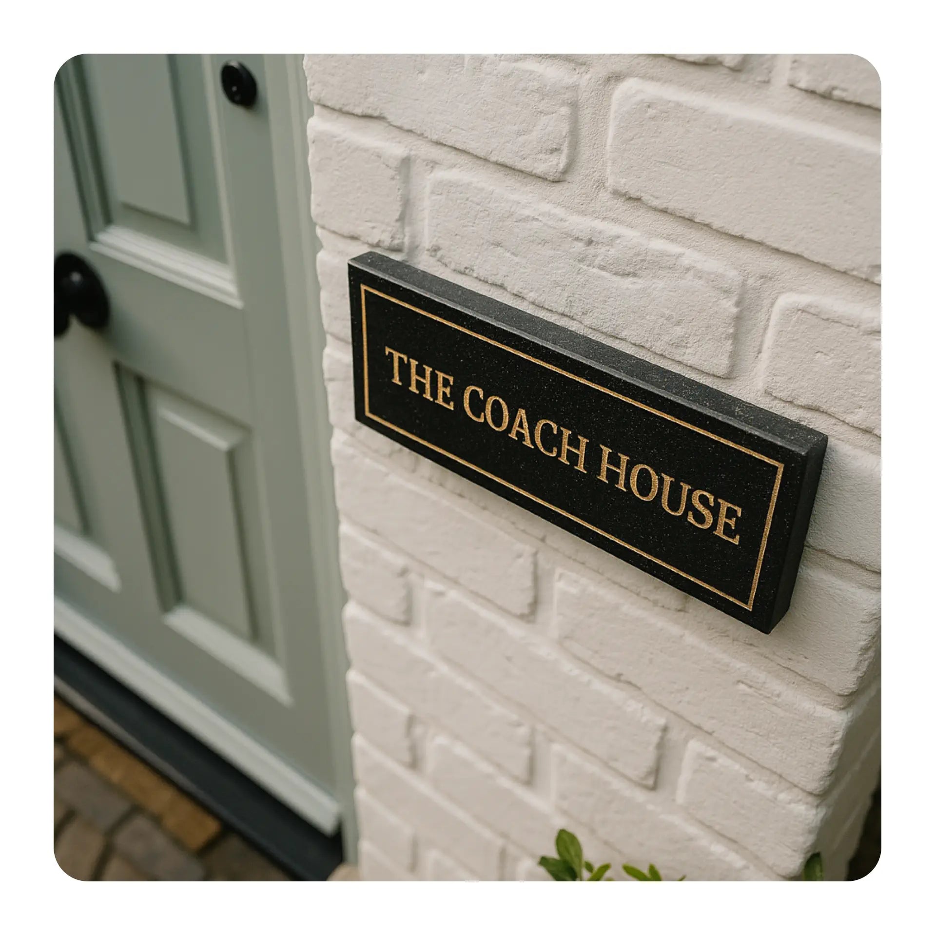 Door sign reading 'The Coach House' on a brick wall next to a door.