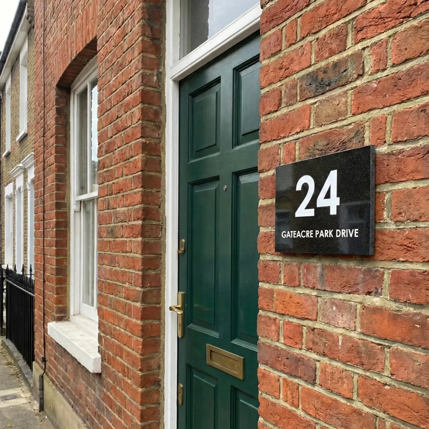 Granite house number sign on a brick wall with '15 Barton Wood Road' text