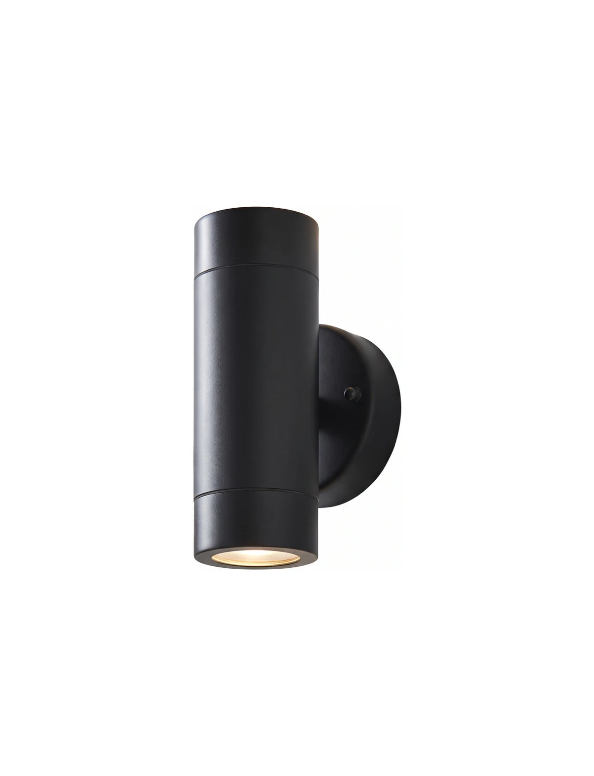 The image shows a modern grey cylindrical outdoor wall light mounted on a white textured wall. It emits both upward and downward light, creating a stylish and balanced illumination. Greenery on either side enhances the sleek and contemporary look of the fixture.