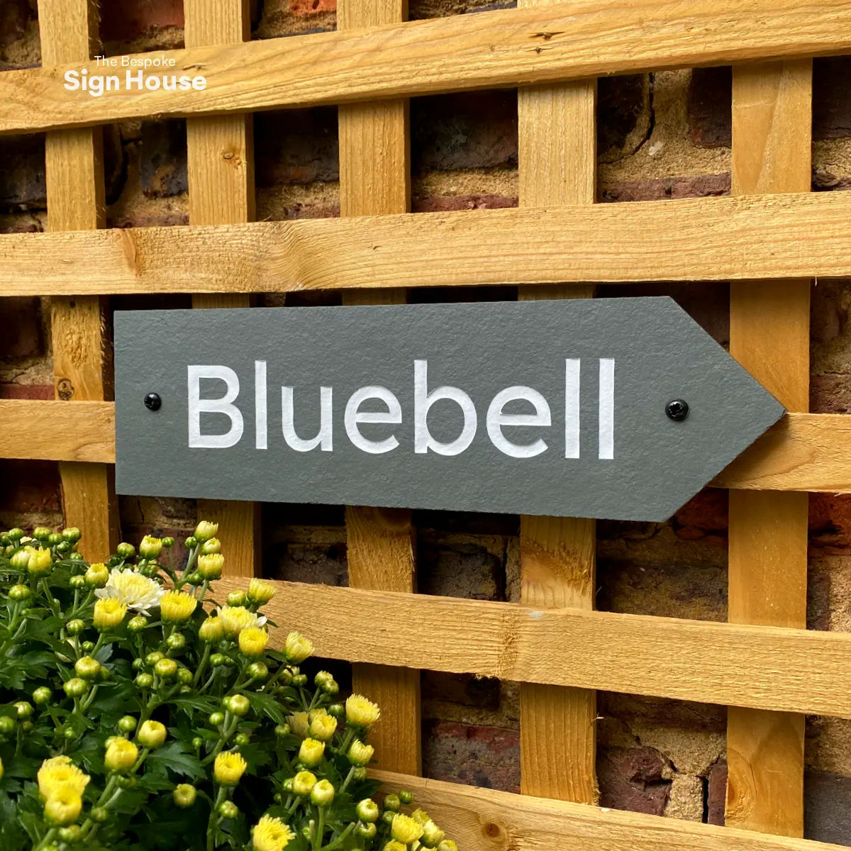 a grey slate house sign with a house name and an arrow cut into the right hand side