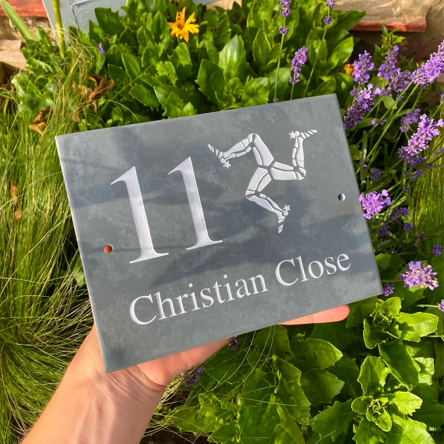 a house number sign for a doorway with the isle of man trio leg emblem