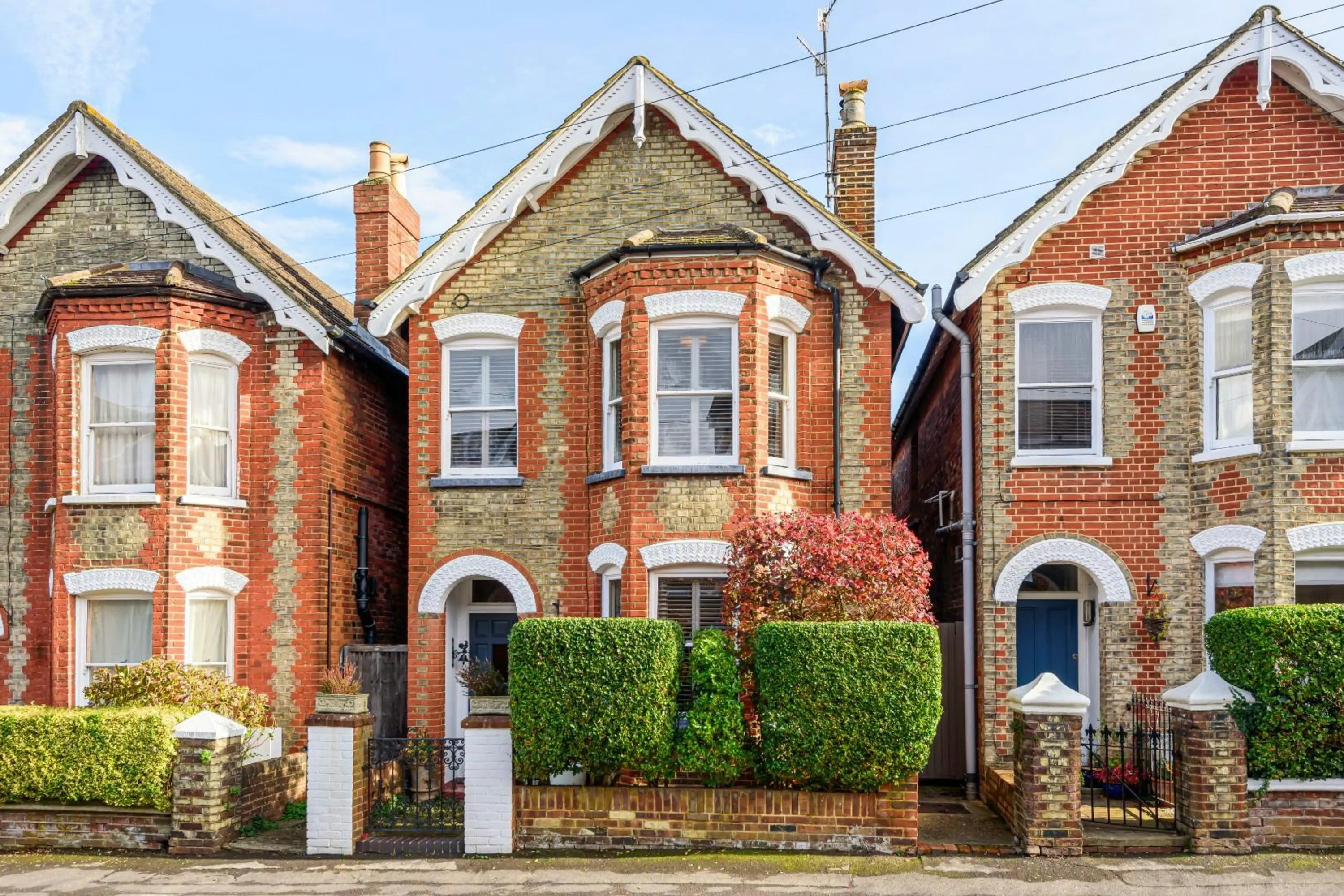Three brick houses with white trim on a residential street.