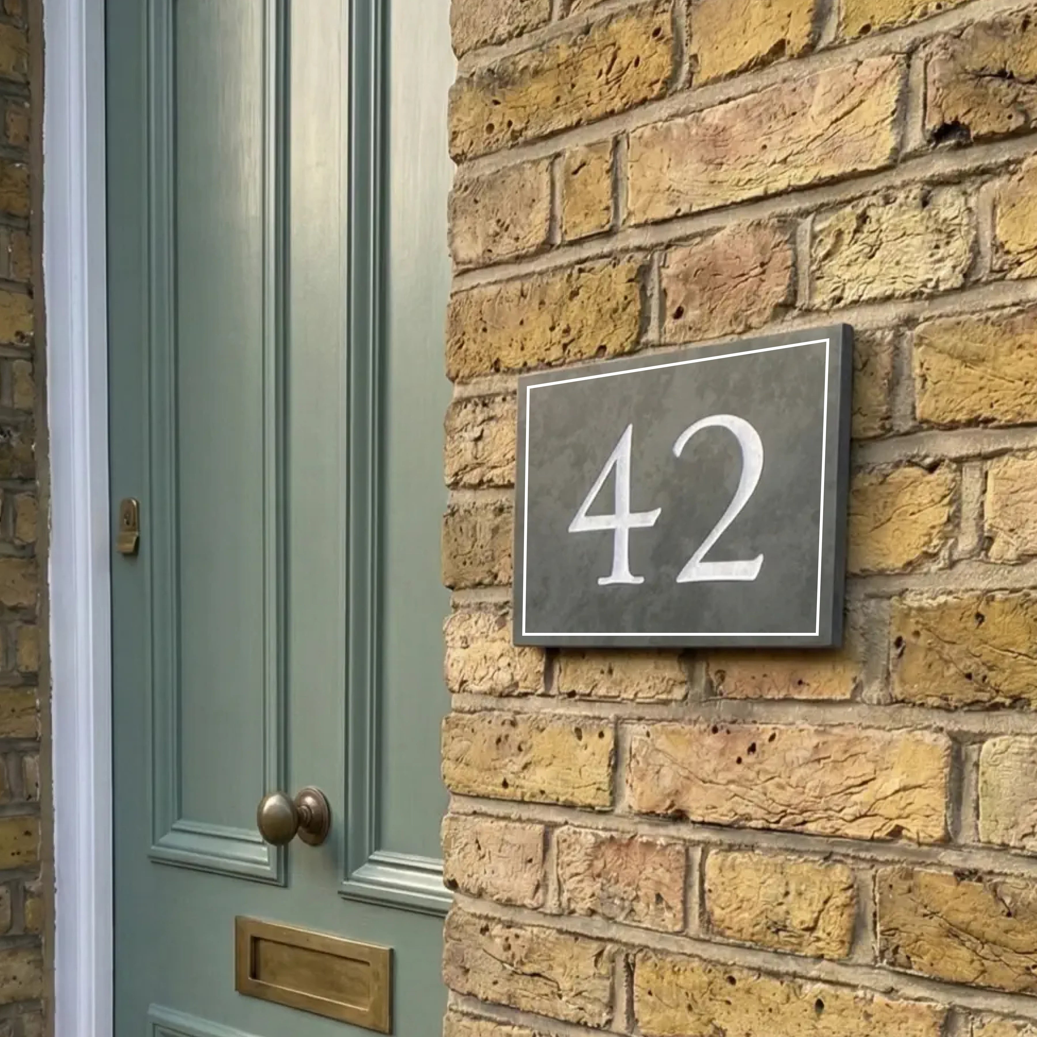 House number 42 on a brick wall next to a green door.