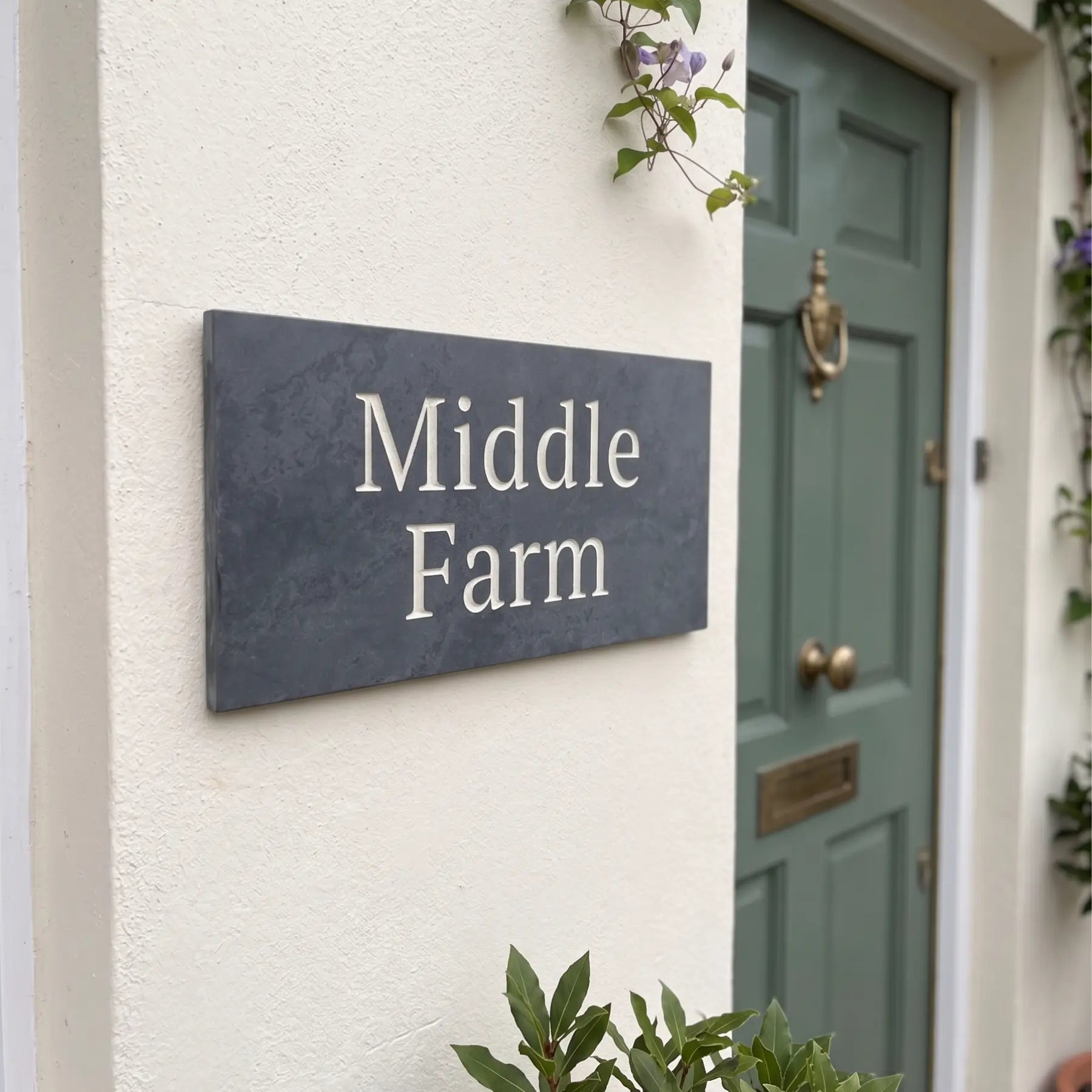 House sign with 'Middle Farm' on a white wall next to a green door.