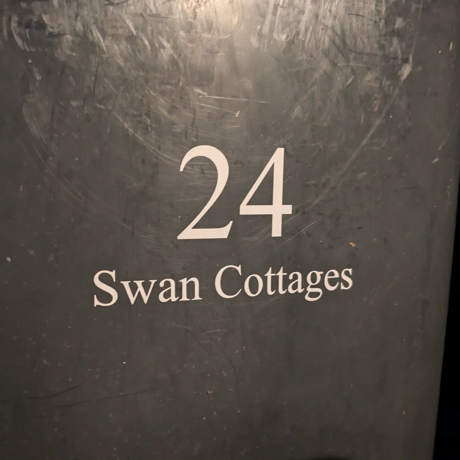 Black bin with '64 Oakley Close' printed on it, set against a blurred background of a house and garden.