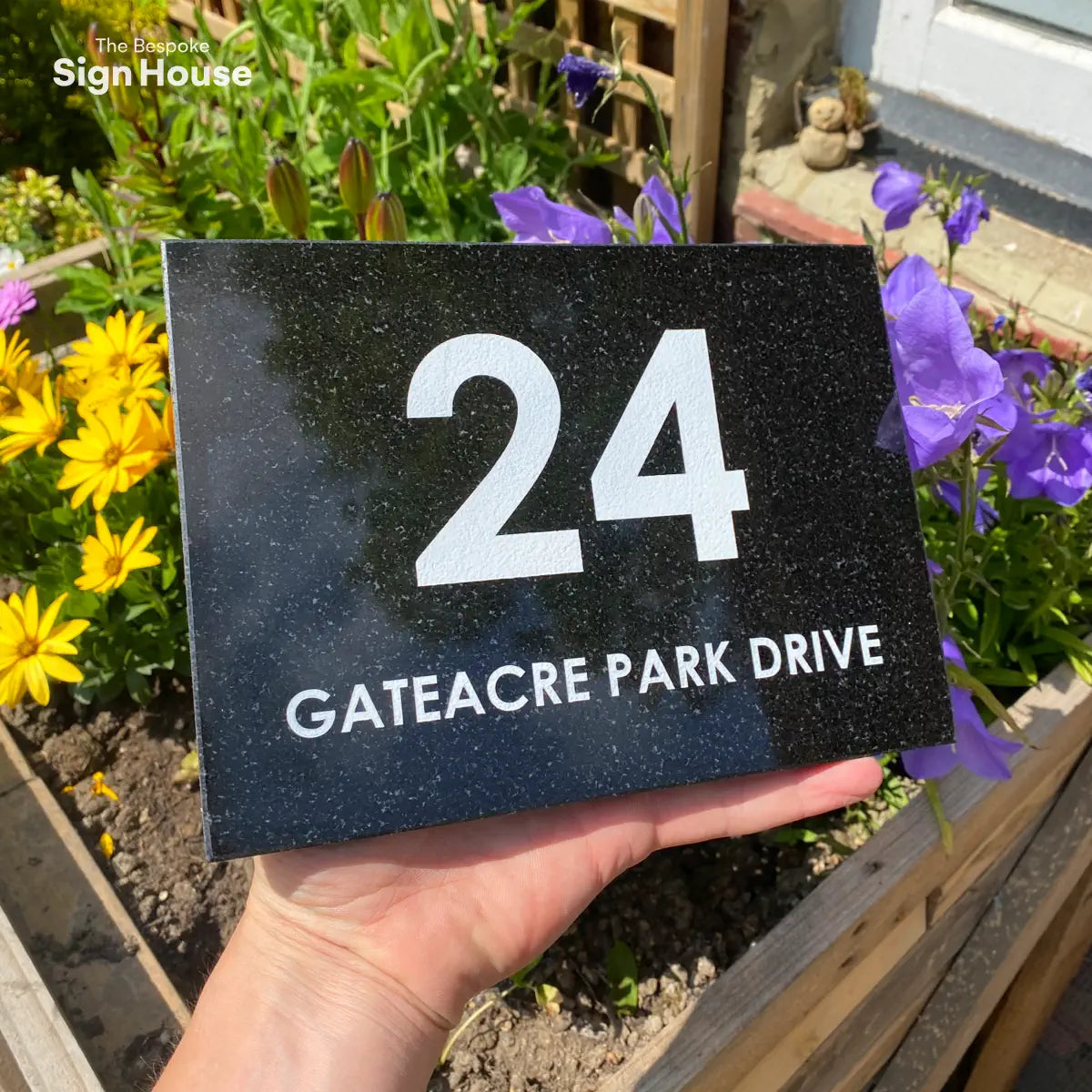 black granite sign with white galaxy effect amongst garden flowers