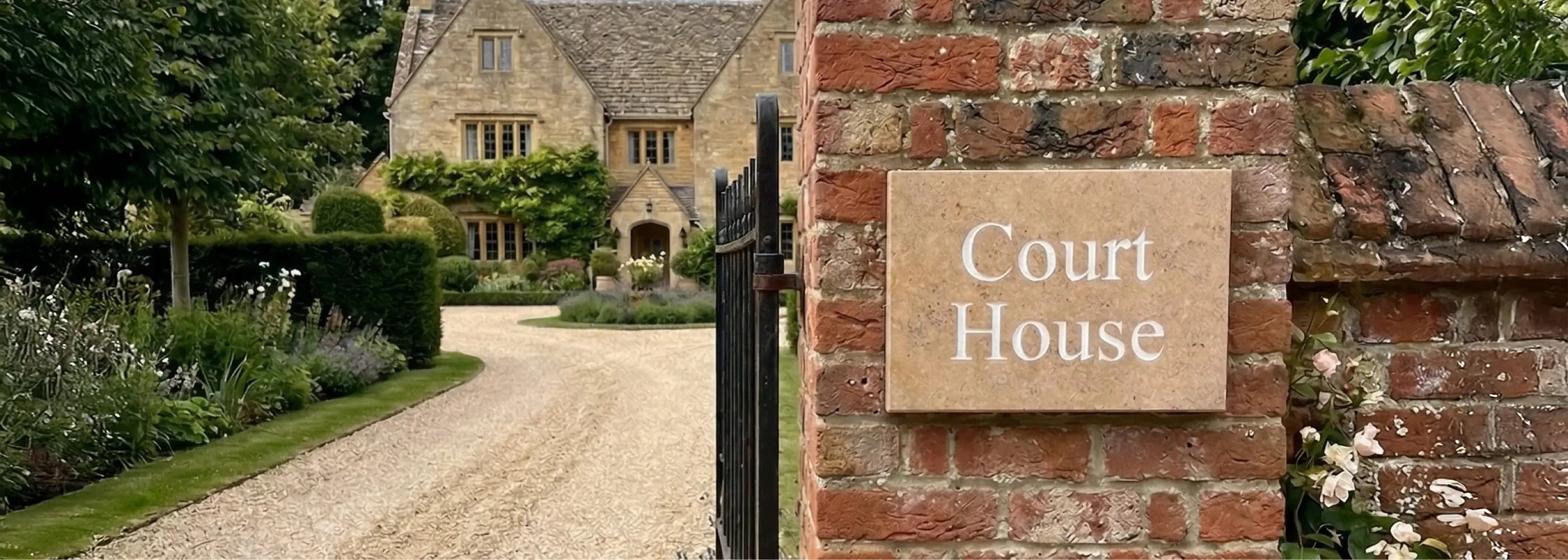 Entrance to a property named 'Court House' with a brick wall and garden.