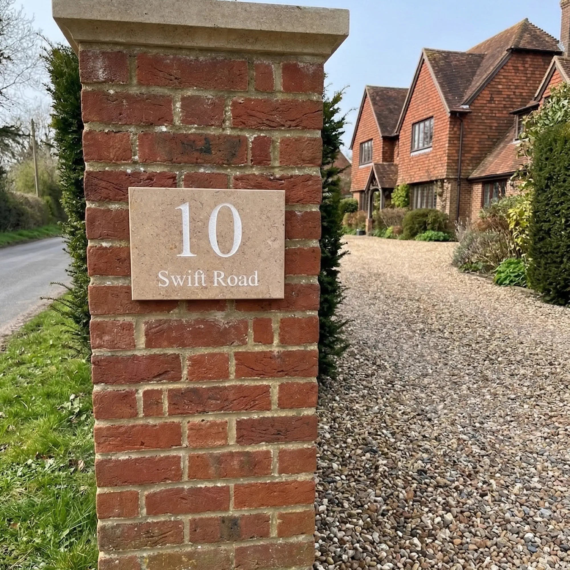 a limestone sign reading 10 swift road on a brick driveway pillar in east sussex