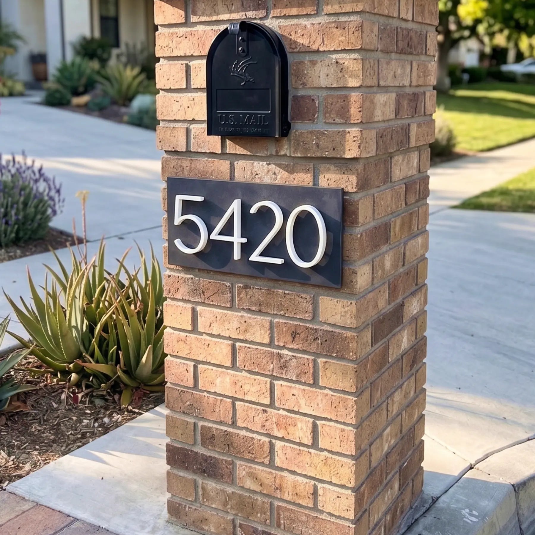 House number 5420 on a brick wall with plants and flowers.