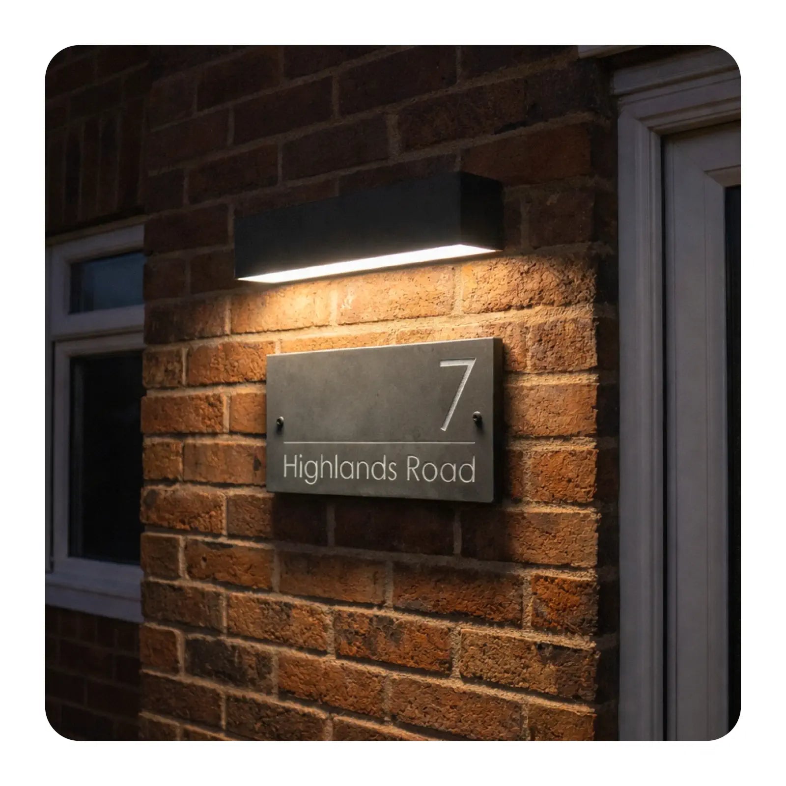 Modern house number sign on a brick wall with a light fixture above.
