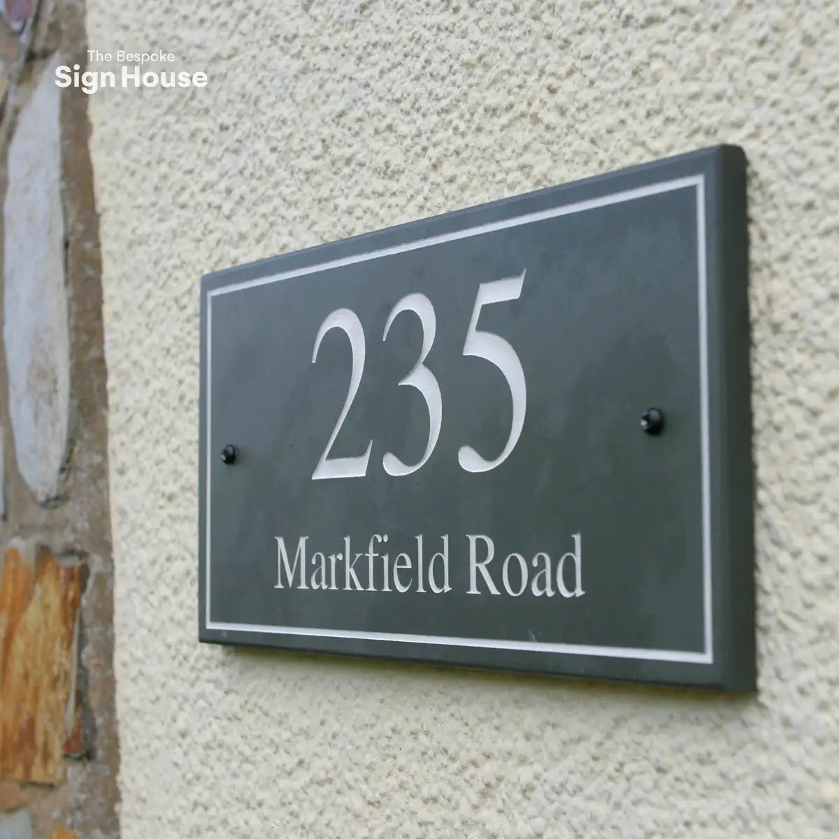 a slate house sign on a british pebble-dashed home