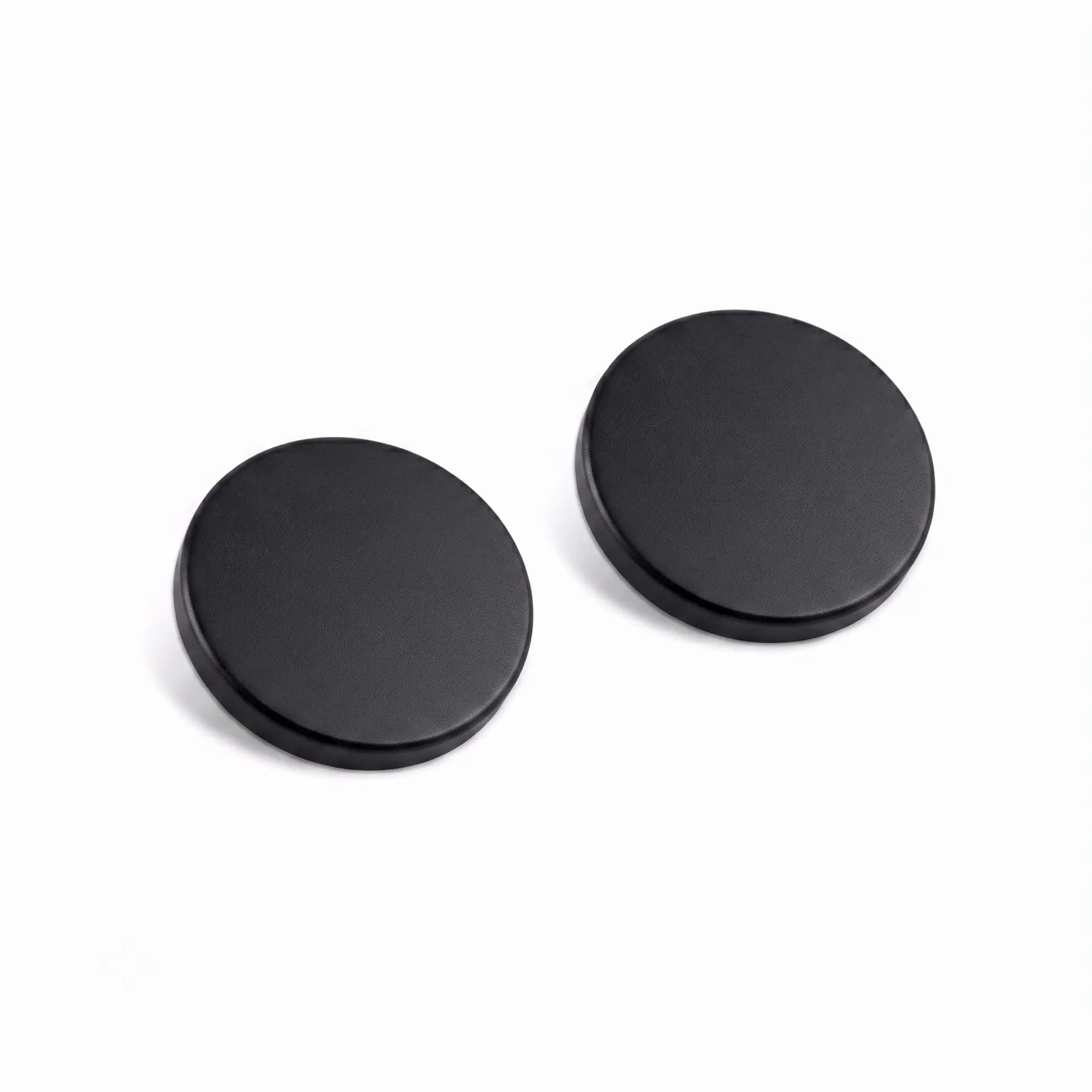 Two round black metal button covers or snap fasteners on a plain white background.