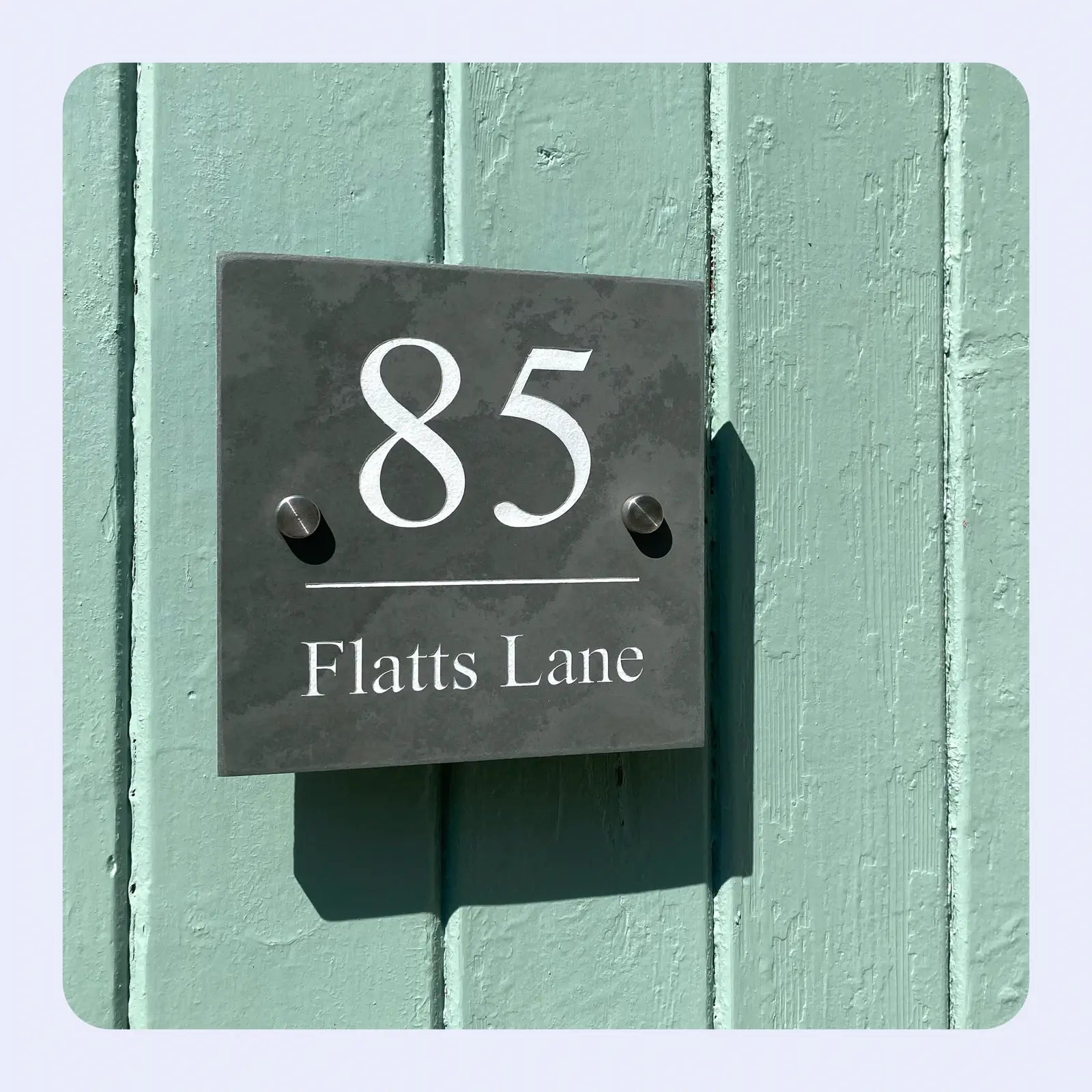 House number sign with '85 Flatts Lane' on a green wall