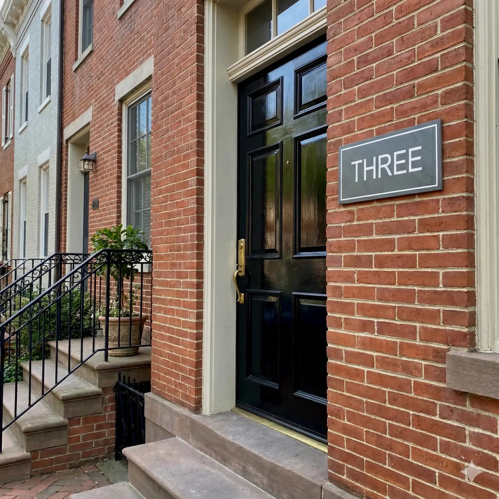 Brick building with a black door and 'THREE' sign