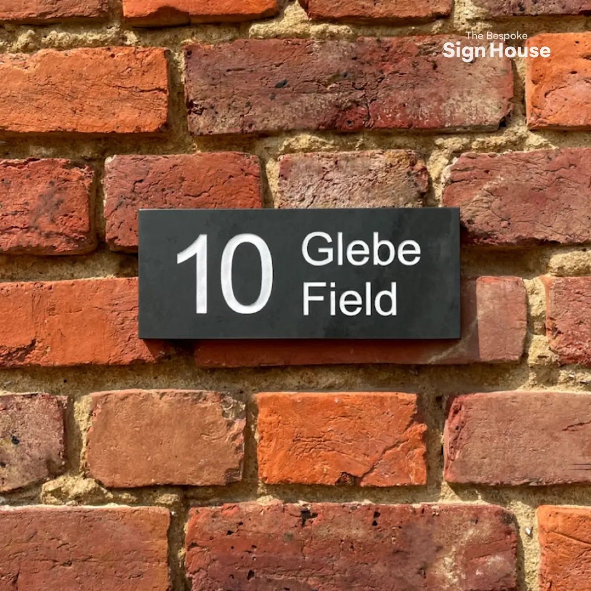 white engraved slate house sign on brick wall