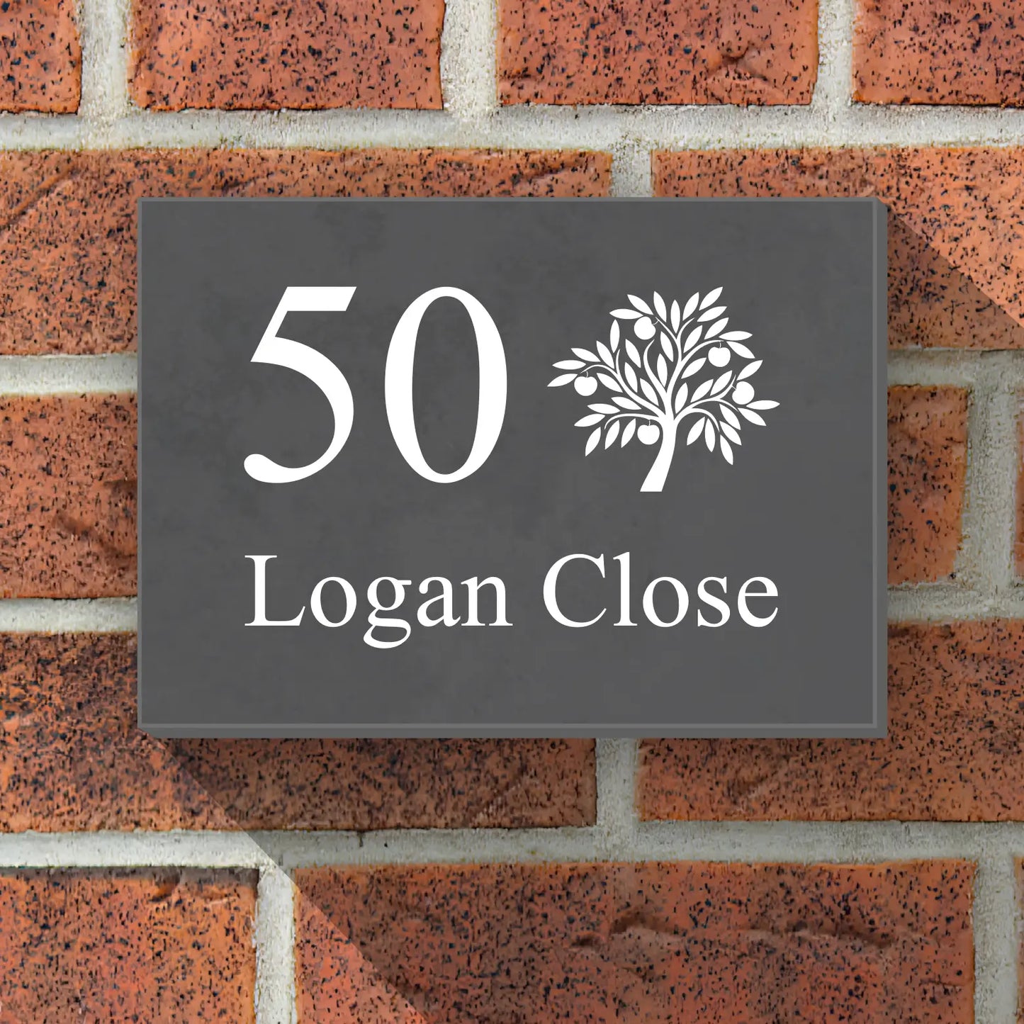 A preview of a slate house sign with a tree and house name, fixed onto a brick wall of a house.