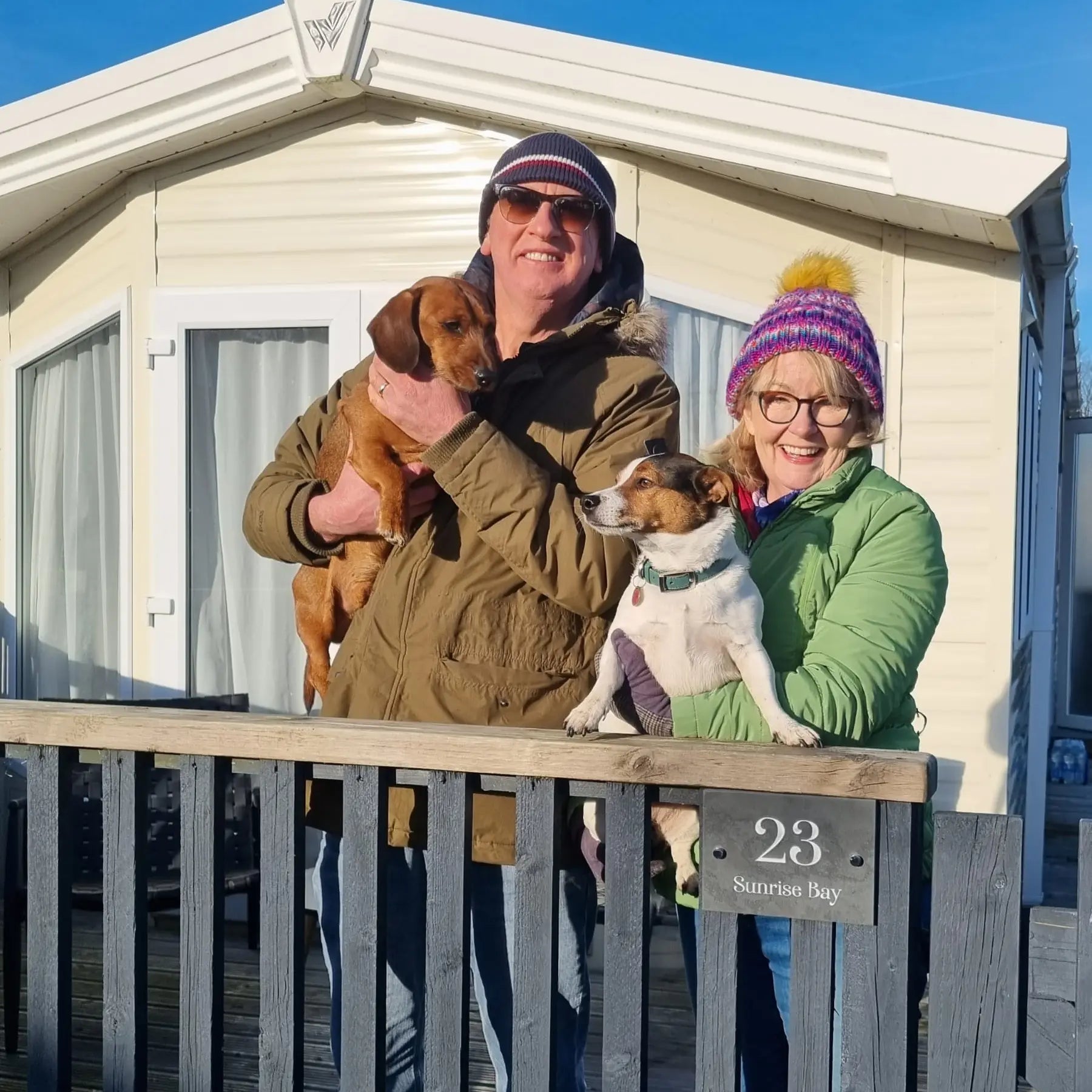 files/slate-sign-on-holiday-caravan-fencing-with-happy-couple-and-dog.webp