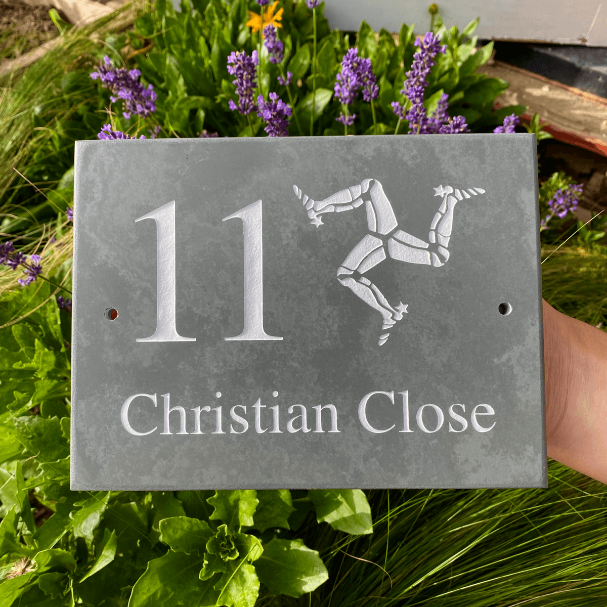 slate house sign with address number and name engraved and painted white alongside the isle of man triskelion