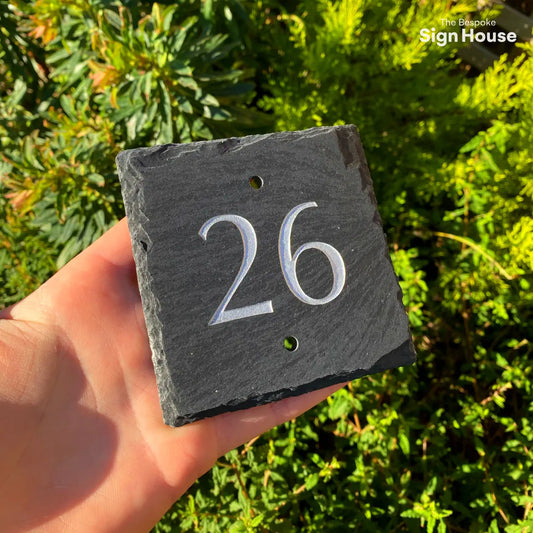 a silver number 26 engraved and painted into a small slate sign