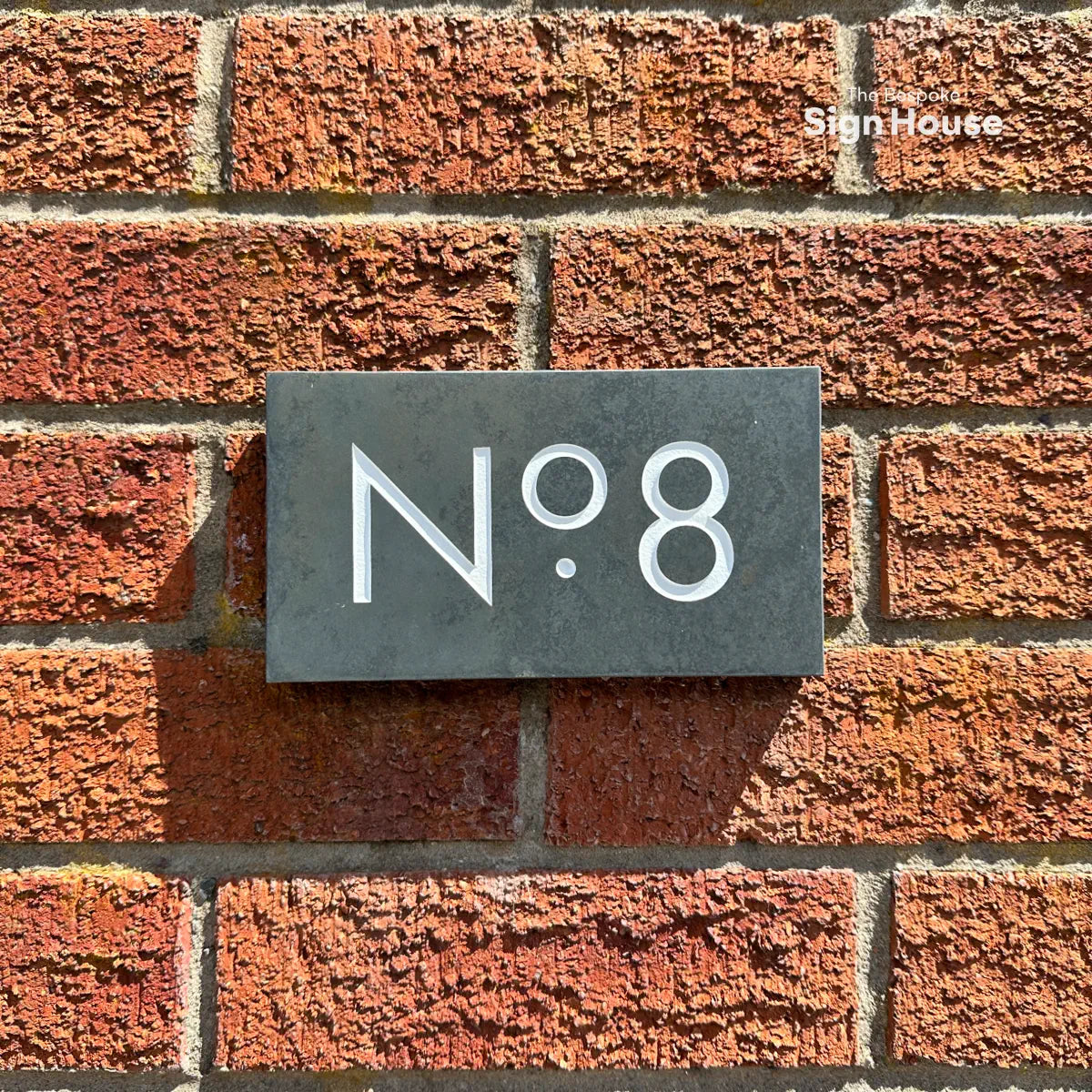 smart looking slate number sign on red brick wall