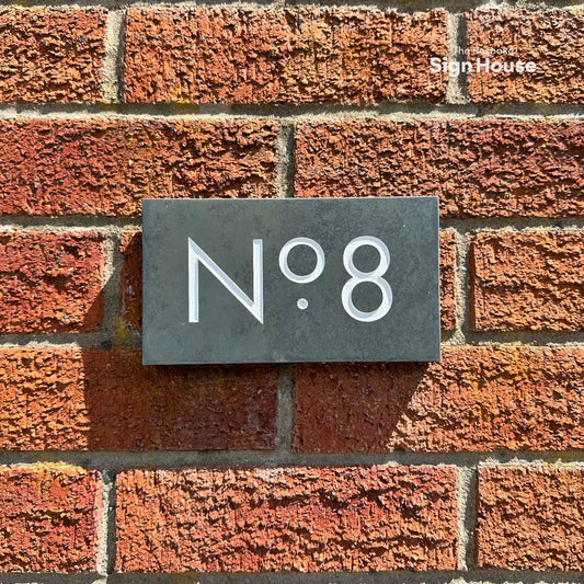 smart looking slate number sign on red brick wall