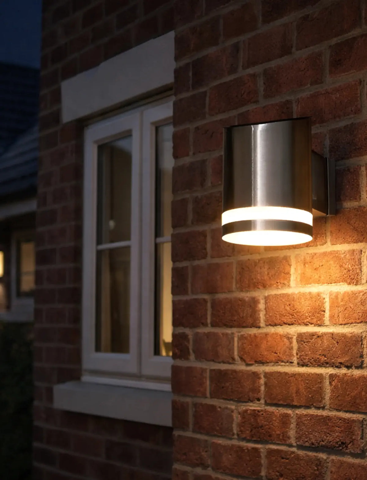 Outdoor wall light fixture on a brick wall next to a window
