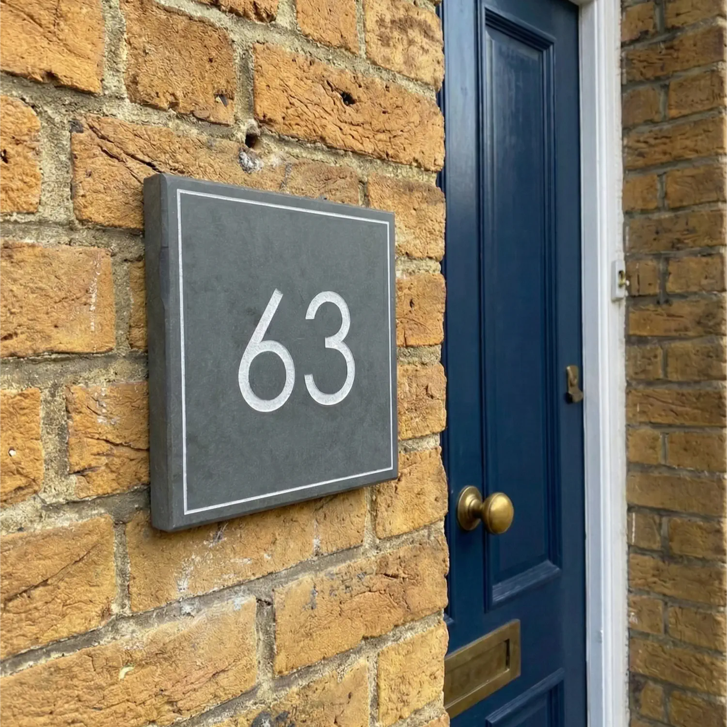 House number '63' on a brick wall next to a door