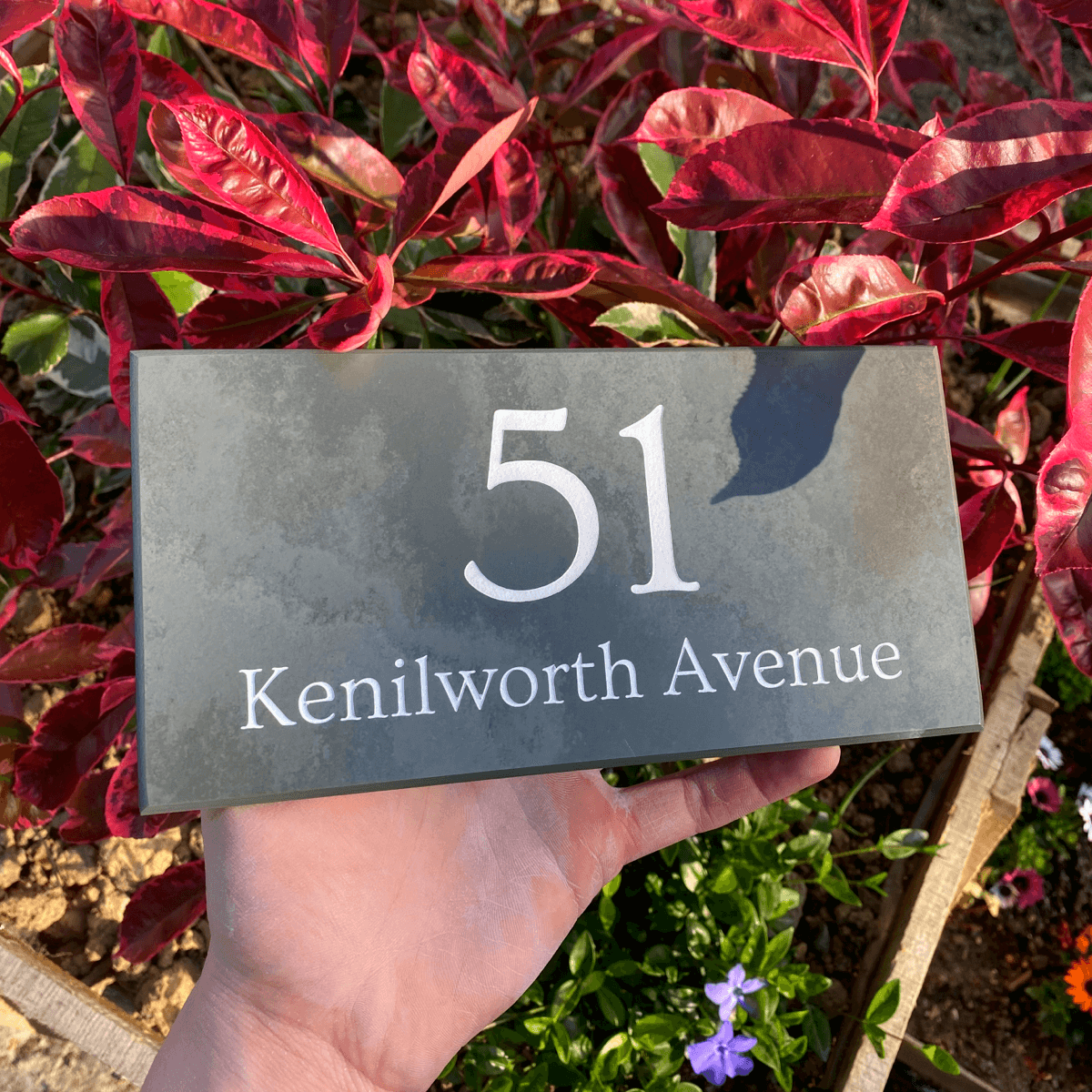 stunning slate house sign with house number and road name engraved and painted white. Sign is against red foliage