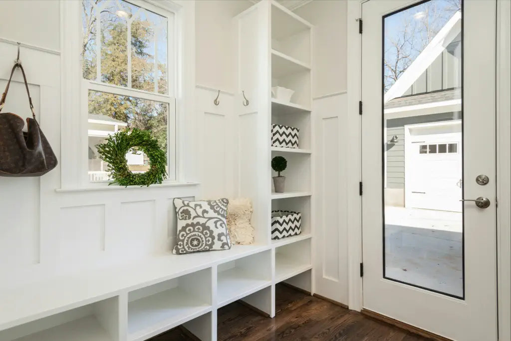 a white open storage cupboard on the wall next to the front door