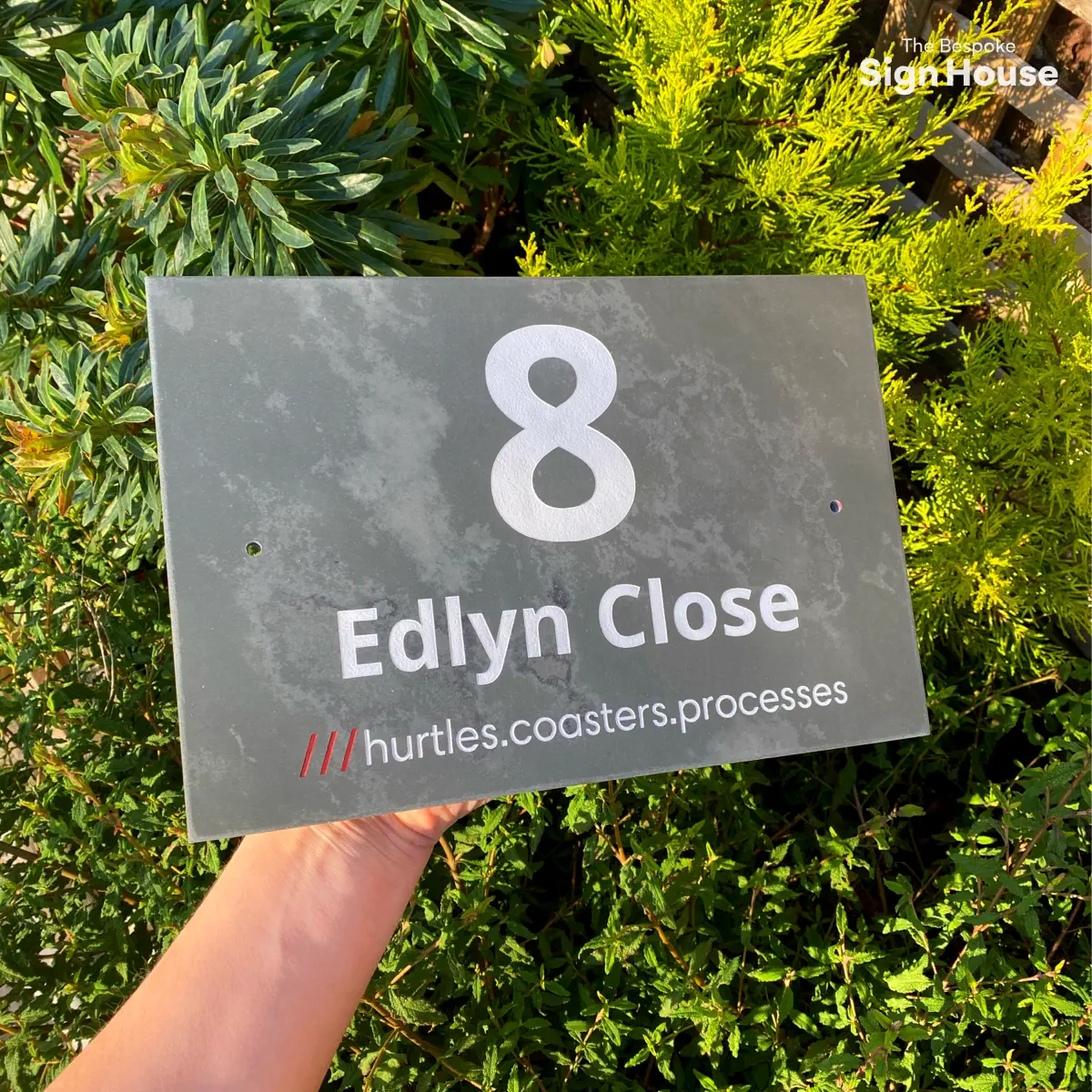 a large slate sign with a white number 8, white text saying Edlyn Close and a what3words address reading ///hurtles.coasters.processess