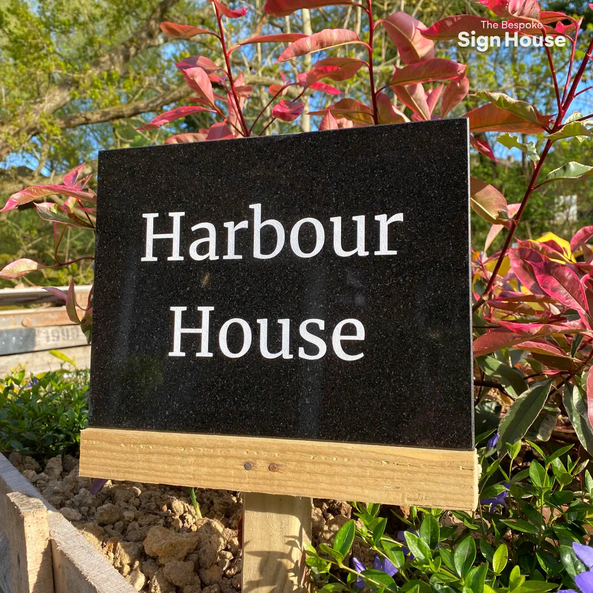 large black granite house name sign with the text Harbour House engrave into it and sprayed with white paint