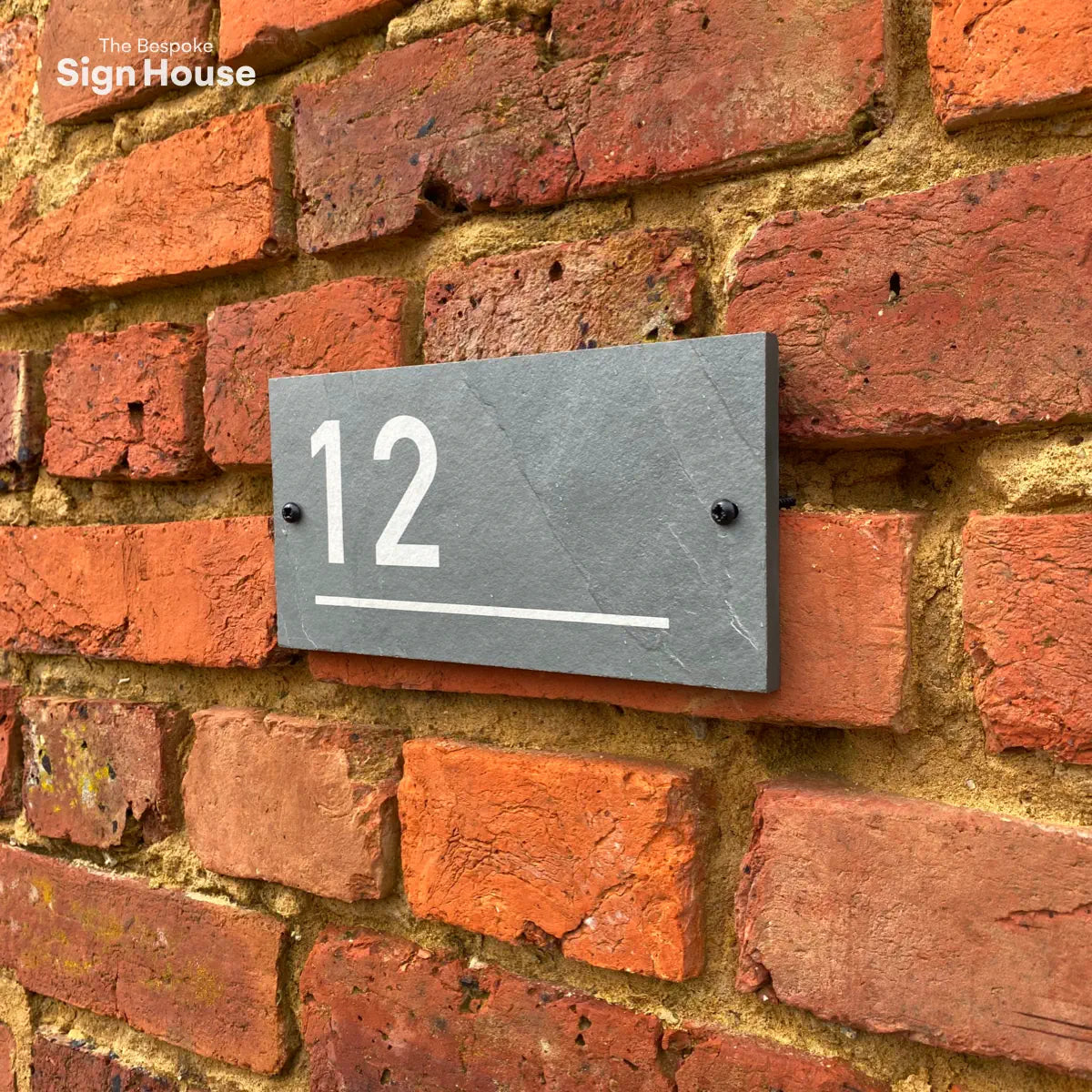 slate house sign with number and decorative line engraved on it